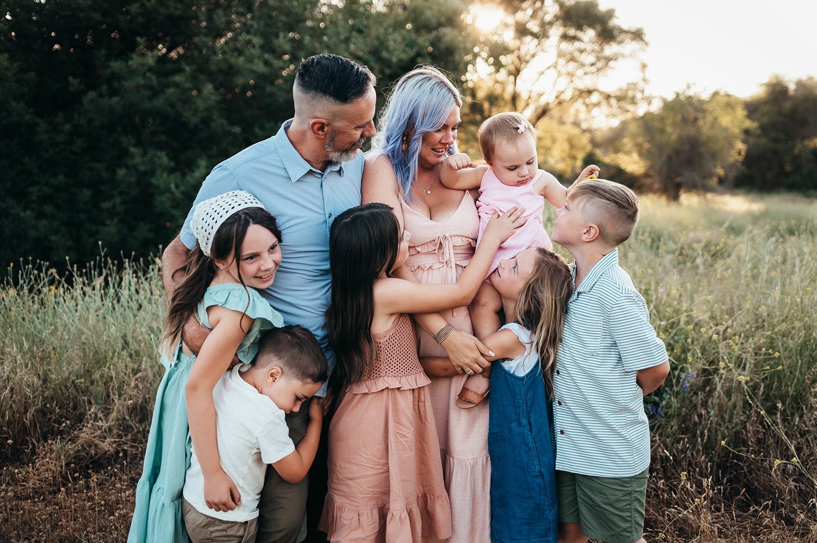 Family of 8 cuddling in sunset light during the fall.