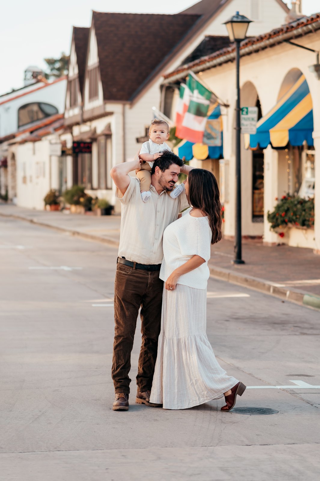 Family walking through Carmel-by-the-Sea village with baby on dad's shoulders during a morning photo session