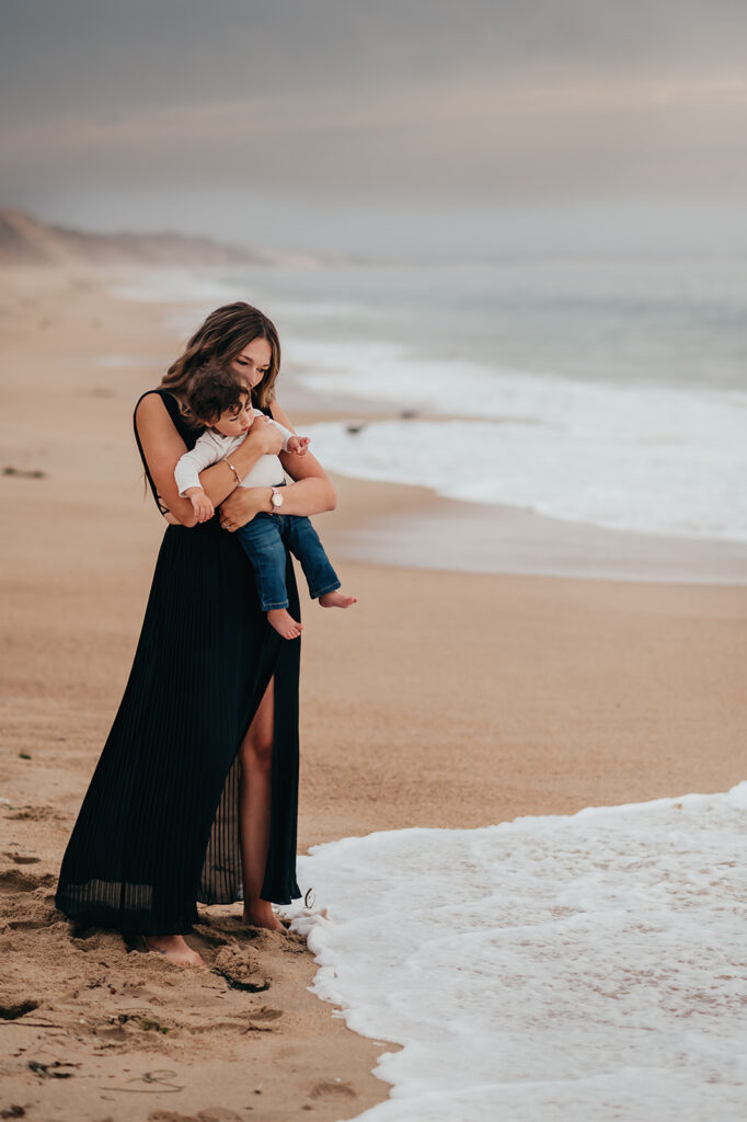 Mom and son walking along the beach at sunset.
