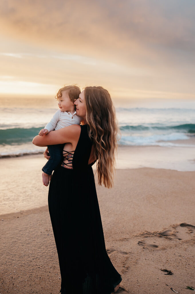 Mom whispering in her son's ear at the beach at sunset along the coast of Monterey.