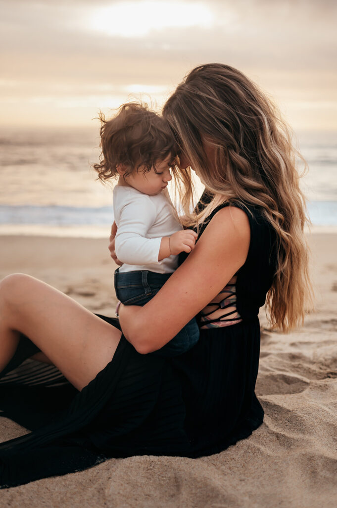 Mom and son snuggled at the beach in Marina, CA.