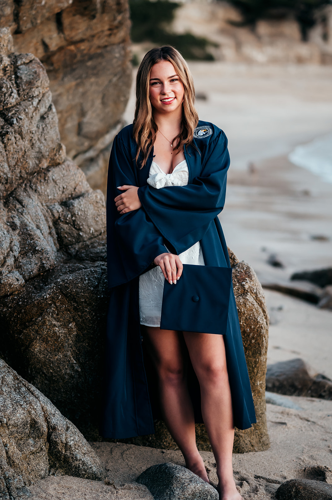 High school senior in cap and gown at a sunrise senior session at Lovers Point Beach in Pacific Grove