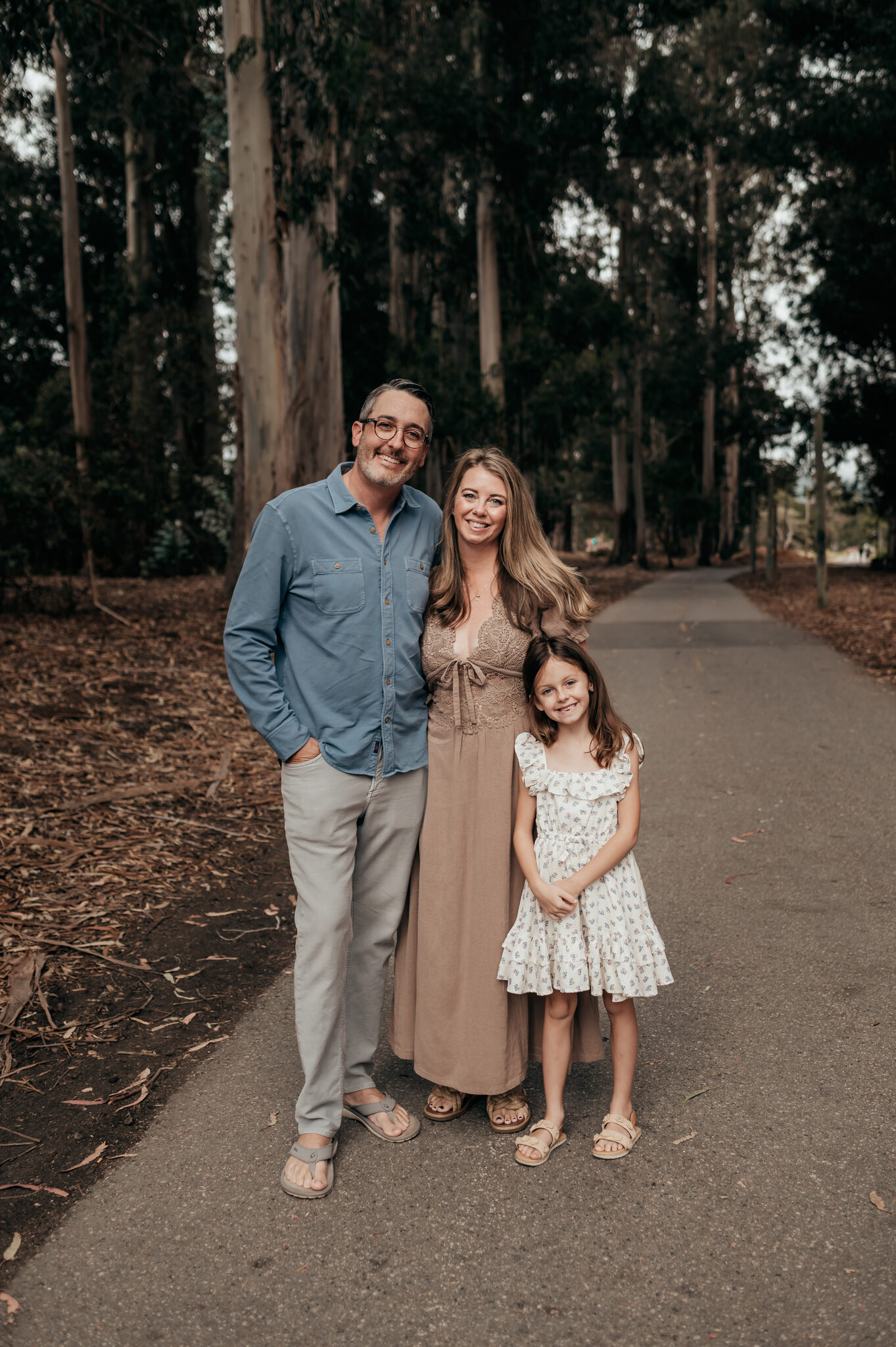 Family of three walking down a path through a eucalyptus grove in Monterey, California