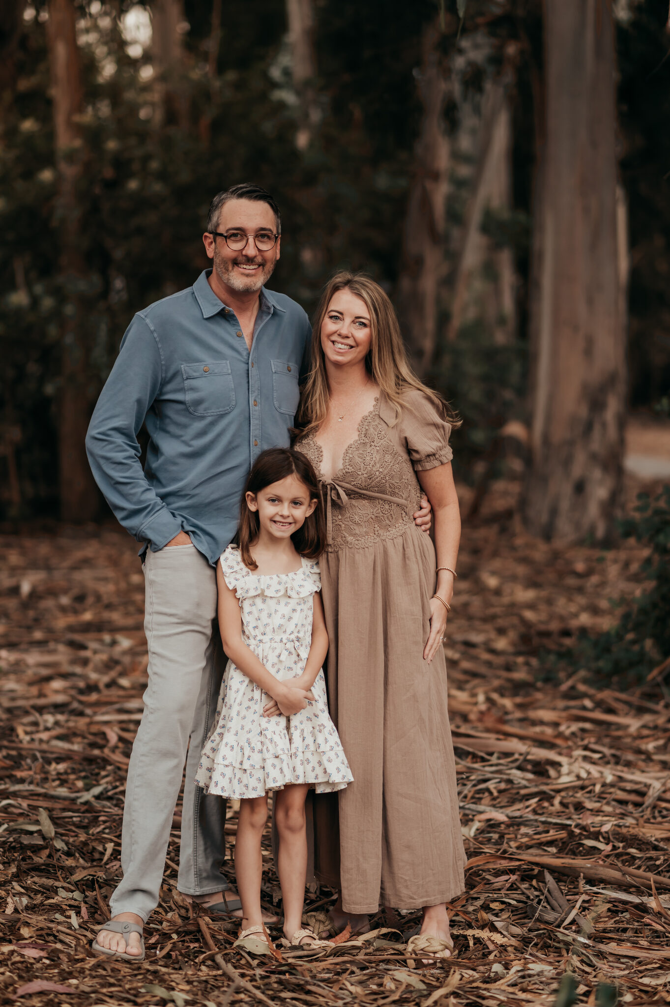 Mom, dad and daughter standing together in a Monterey eucalyptus grove during a family photo session