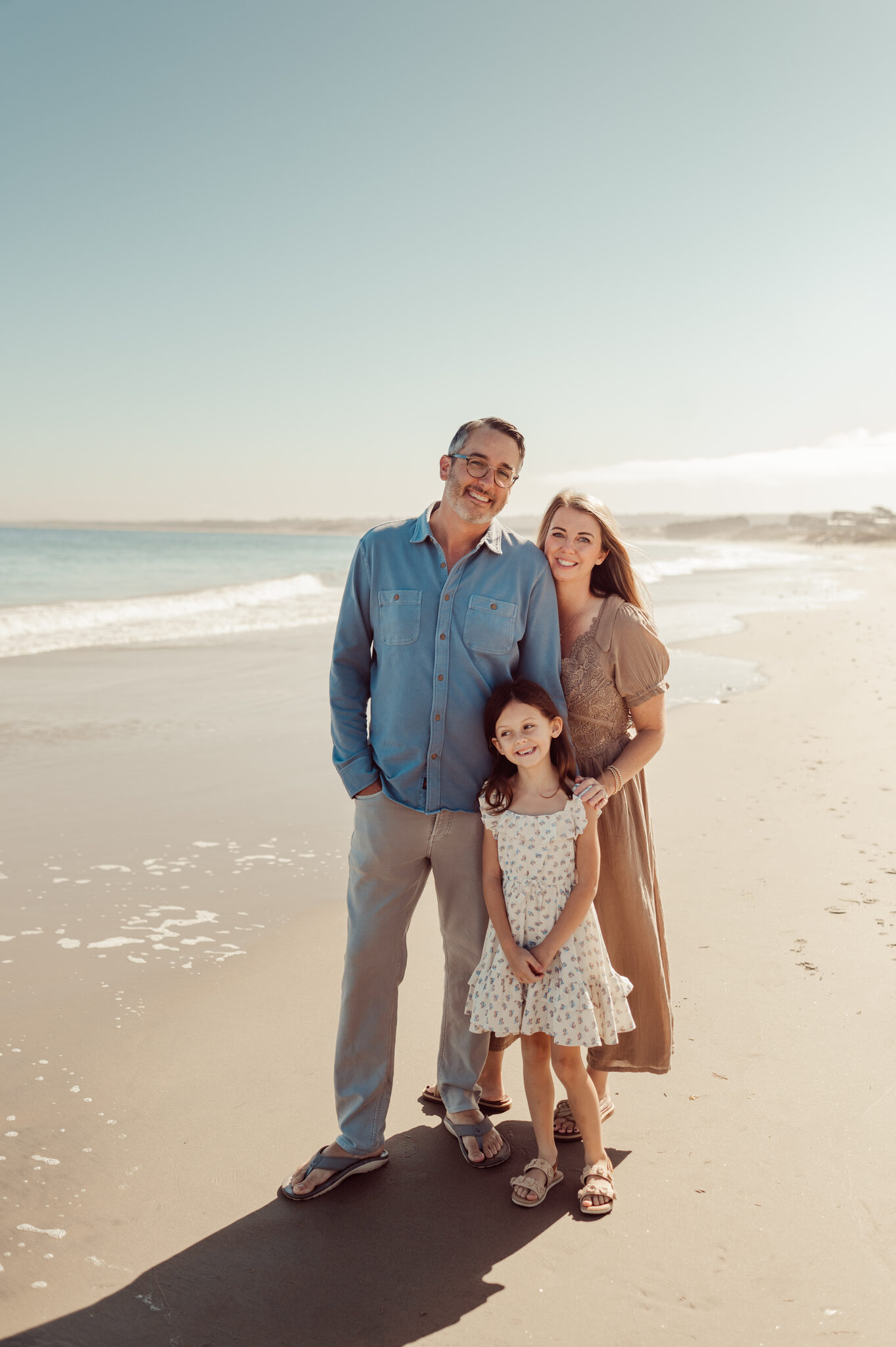 Family of three standing on a white sand Monterey beach in the morning