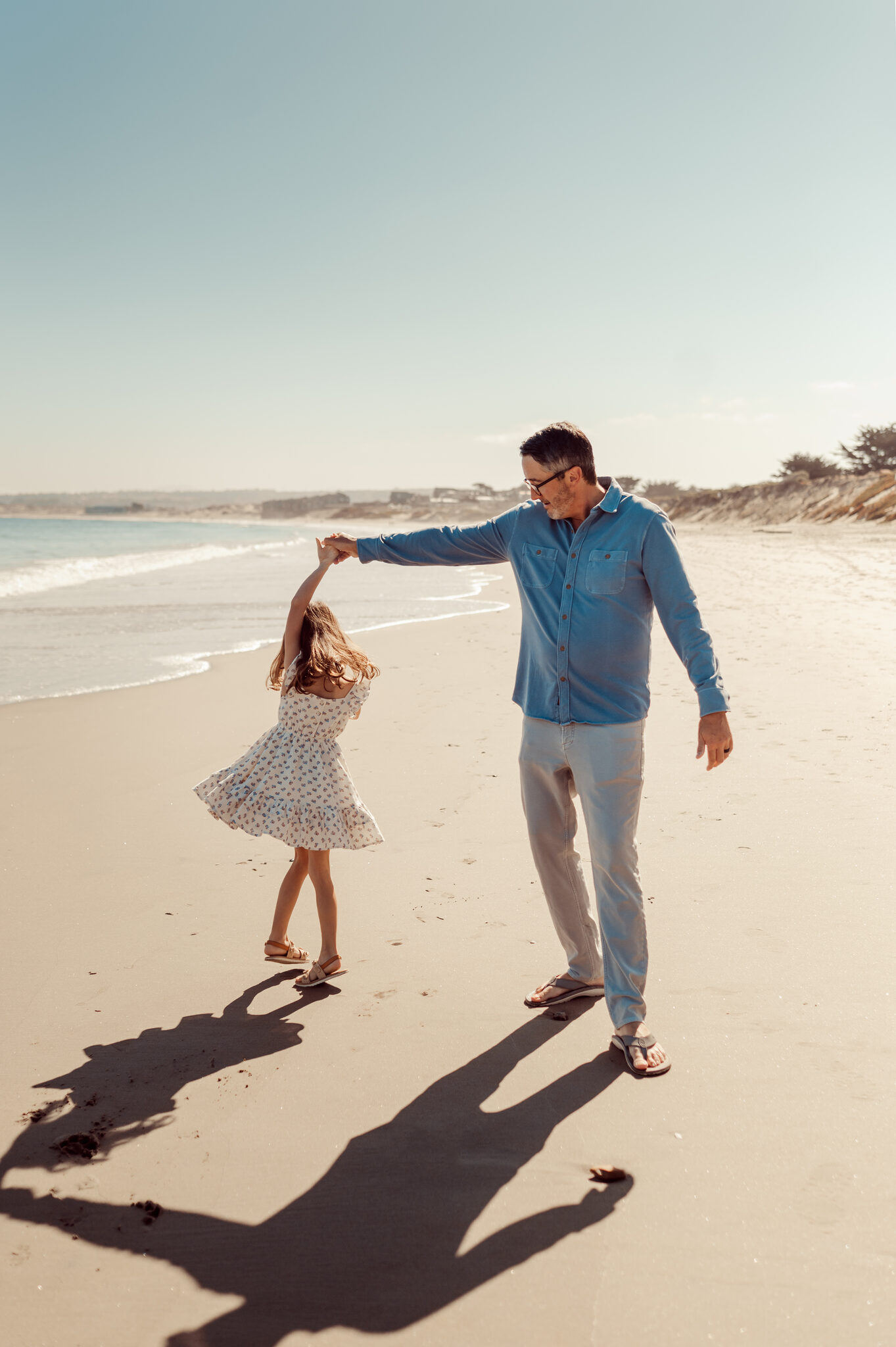Dad twirling his daughter on the sand during a Monterey beach family session