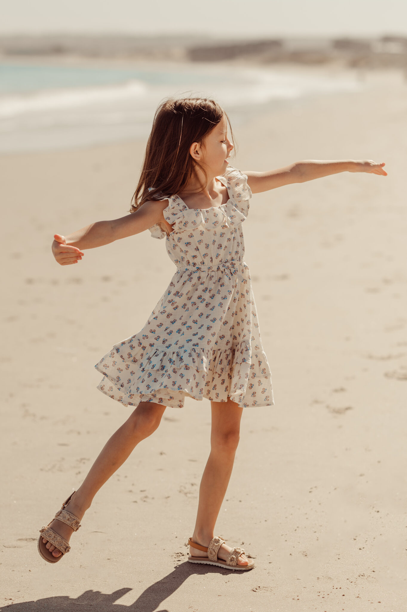 Girl twirling and dancing on the white sand beach