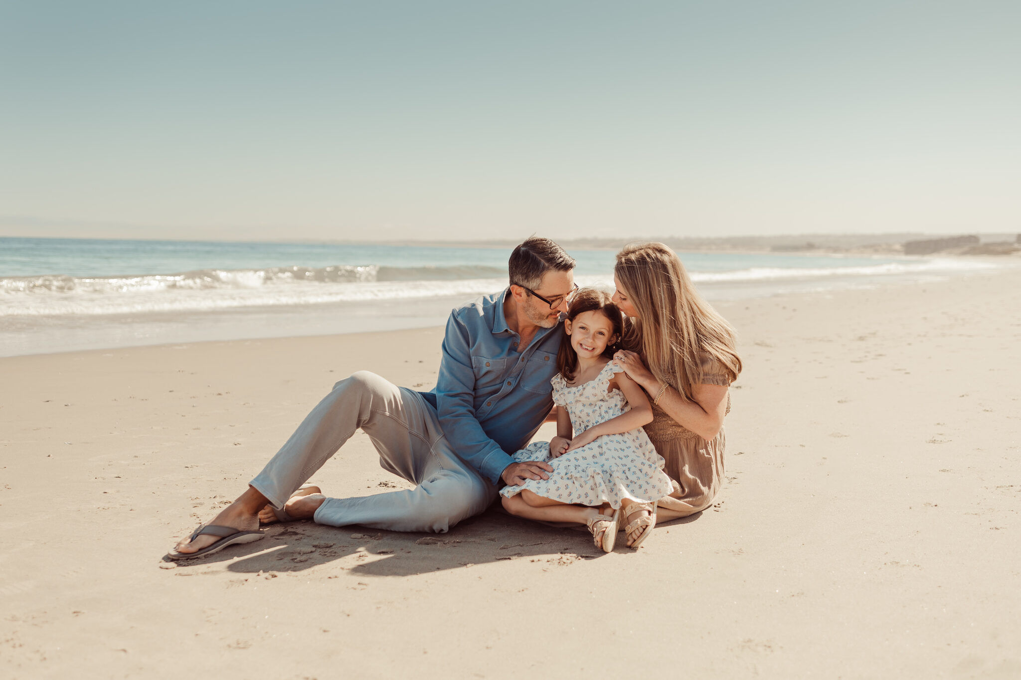 Family sitting together in the sand laughing during a Monterey beach session
