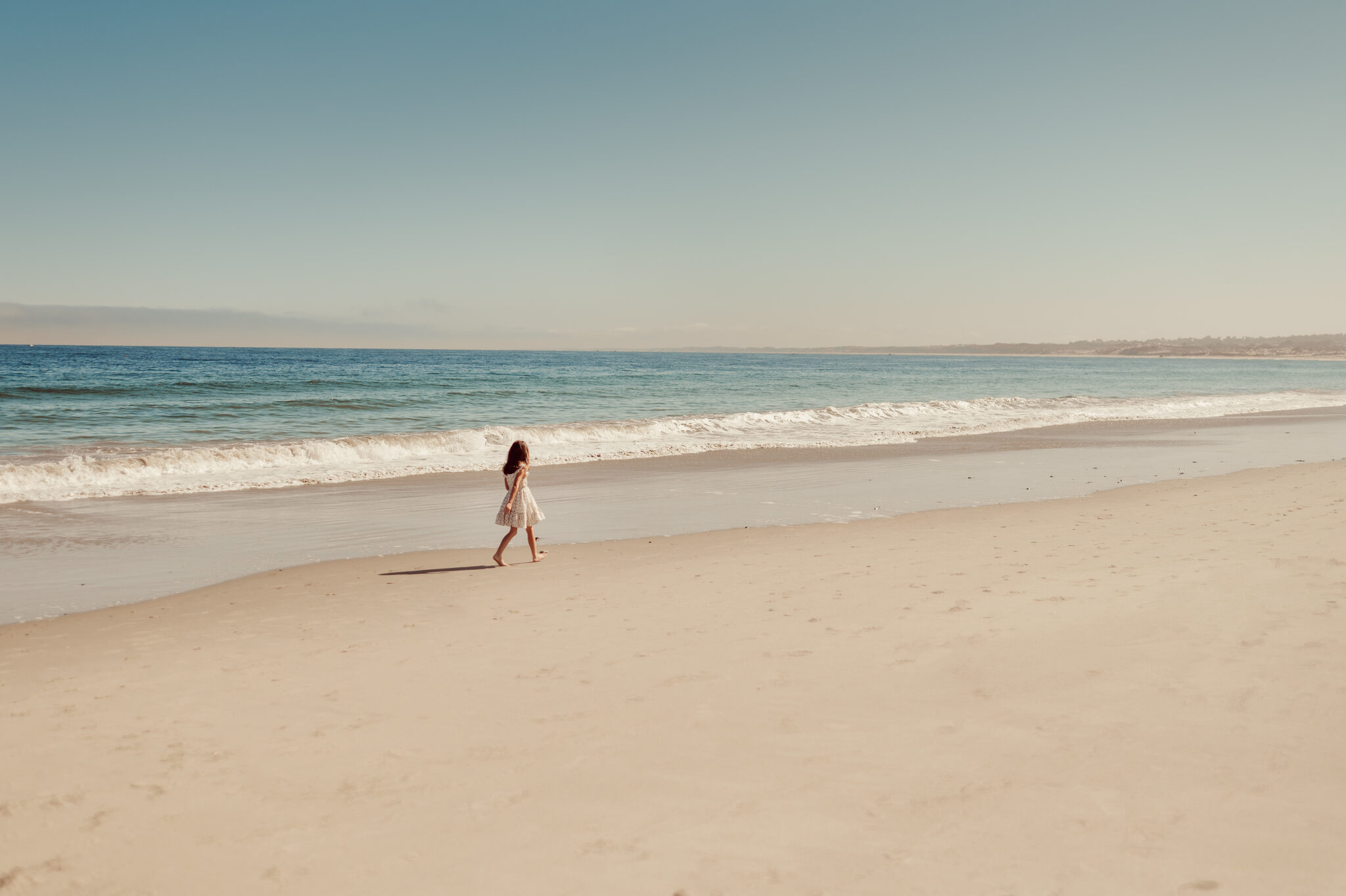 Little girl running down the shoreline of an empty Monterey beach
