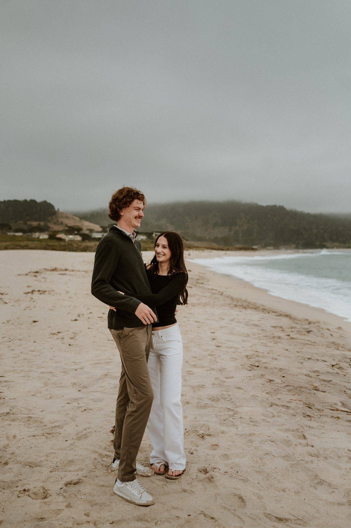 A foggy Carmel River Beach couples session with the couple standing together on the open sand
