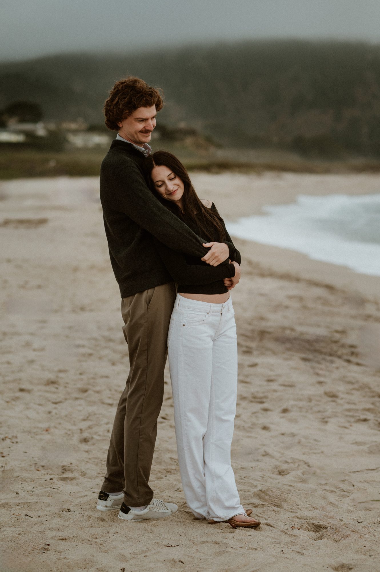 Couple embracing during a Carmel River Beach couples session on a foggy summer evening