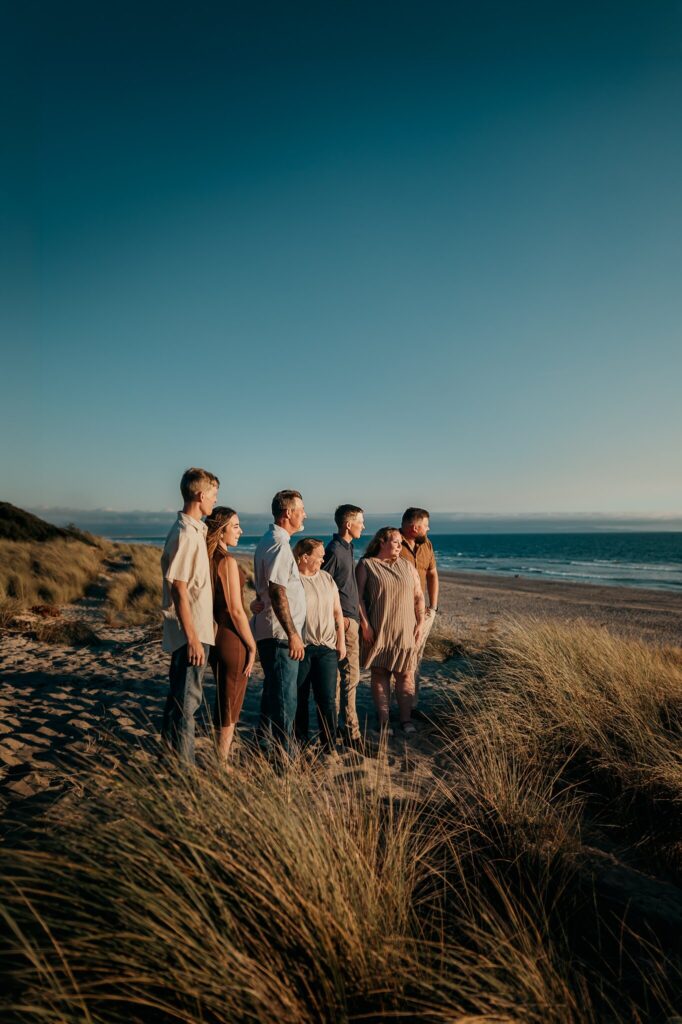 Family of seven standing on the dunes at Pajaro Dunes under a deep blue sky, ocean behind them