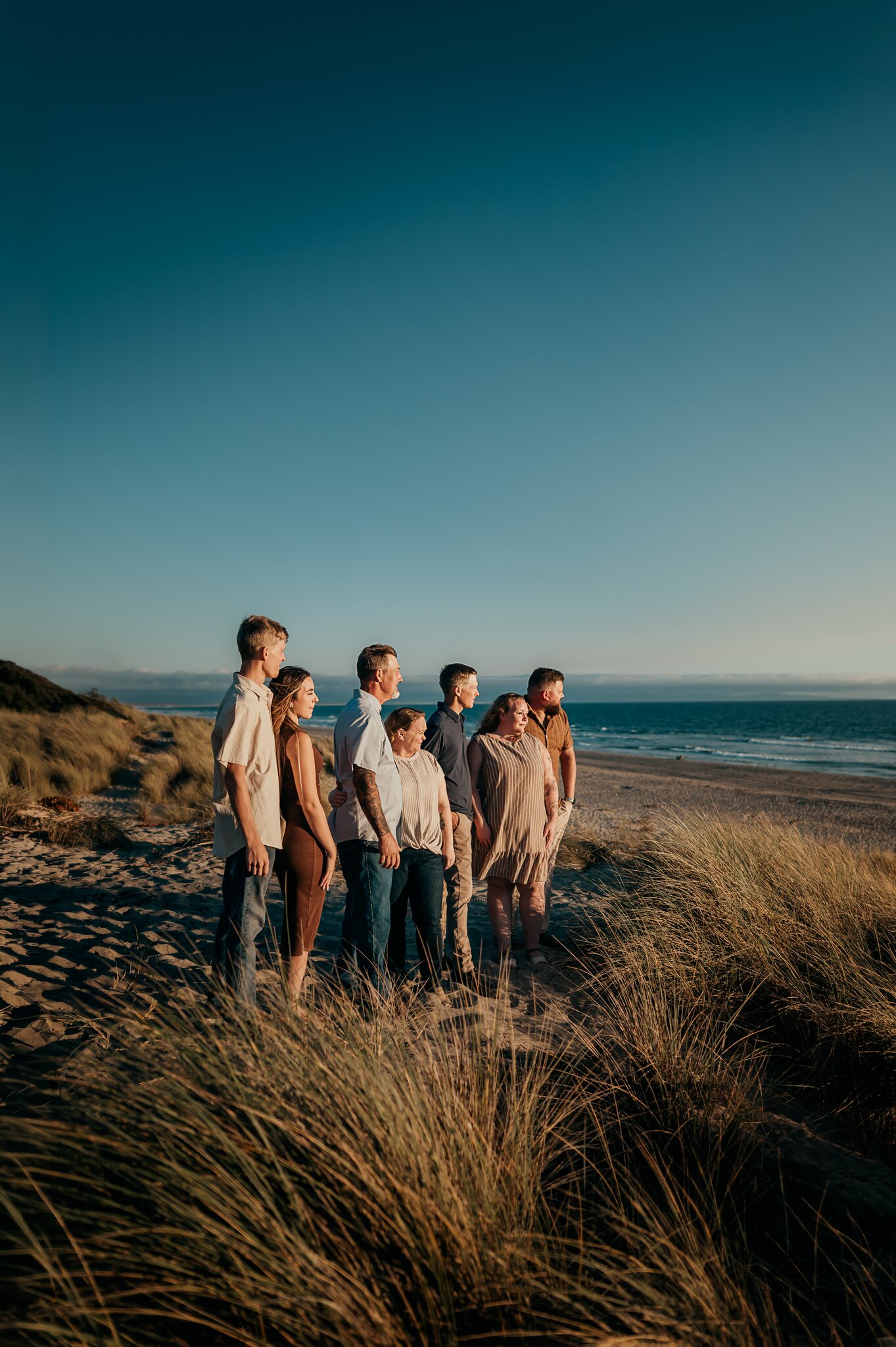 Family of seven standing on the dunes at Pajaro Dunes under a deep blue sky, ocean behind them