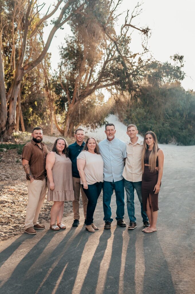 Family of seven on the eucalyptus-lined road at Pajaro Dunes with long golden-hour shadows