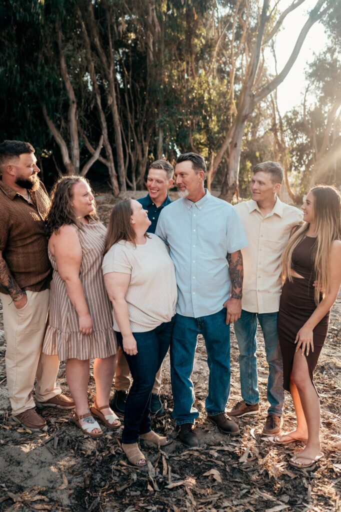 Family laughing together in the eucalyptus grove at Pajaro Dunes in warm backlight