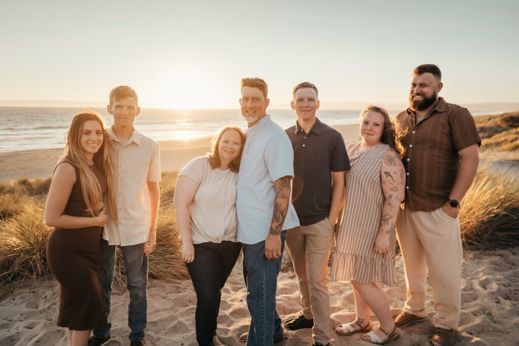 Family of seven smiling together on the sand at sunset, Pajaro Dunes beach
