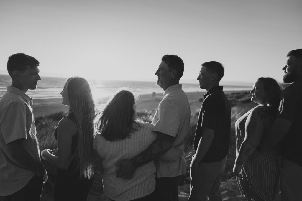 Black and white photo of the family standing in a row watching the sunset at Pajaro Dunes