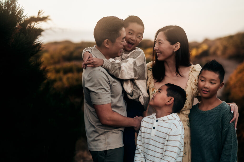 Family hugging and laughing at golden hour on the bluffs in Big Sur