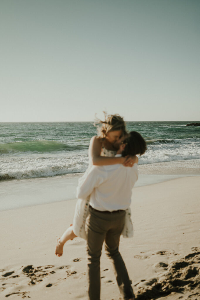 Nick lifting Patrycja into a kiss on the sand at Garrapata Beach in Big Sur