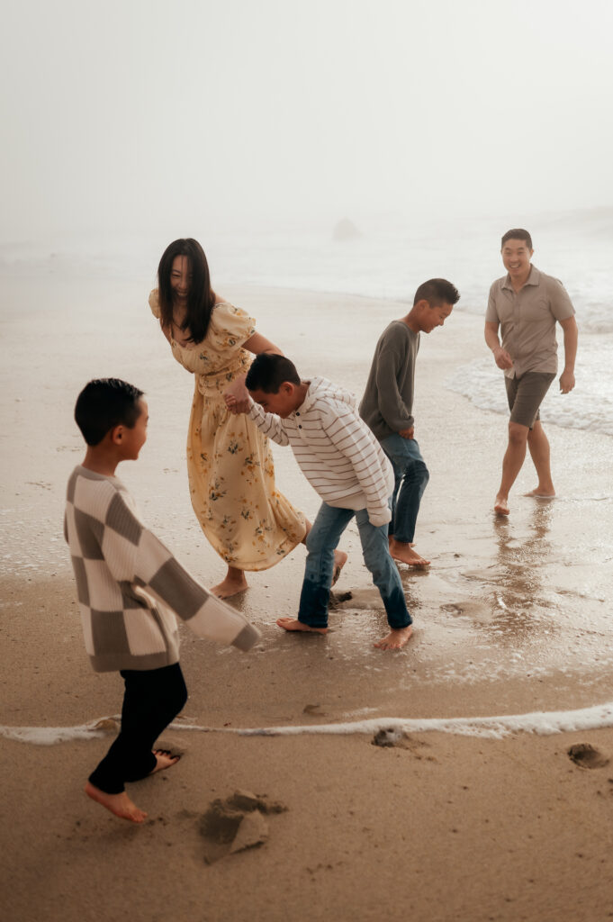 Mom and three boys laughing in the surf during a foggy Big Sur family session