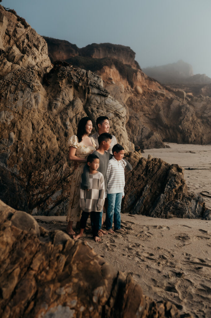 Family standing among coastal rocks at Garrapata State Park as fog drifts over the bluffs