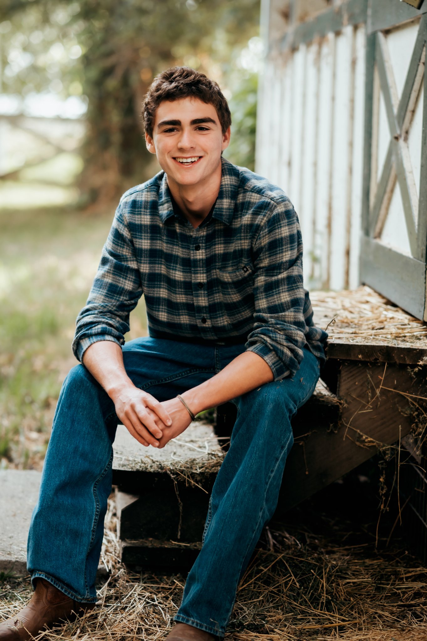 Carmel senior photos: high school senior in a plaid flannel smiling on rustic barn steps at Mission Ranch